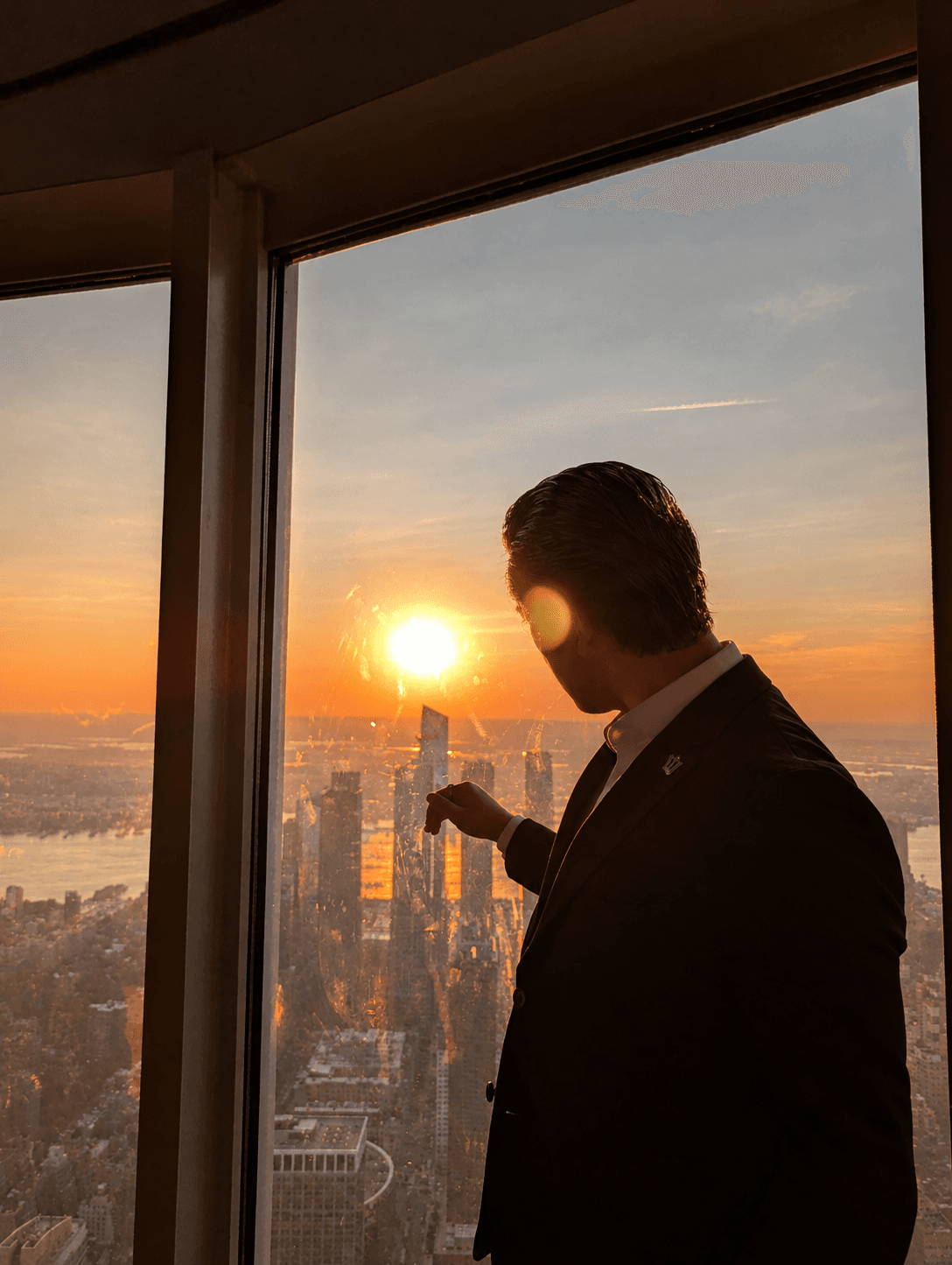 A man looking out over the New York City skyline at sunset